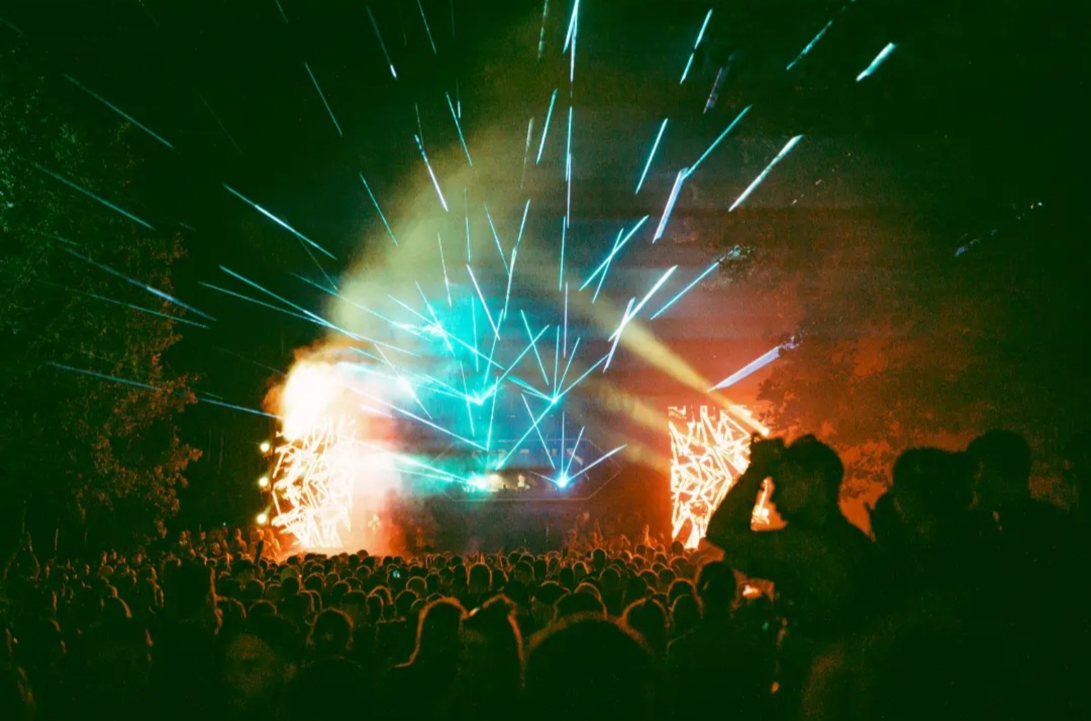 Nighttime festival atmosphere with lasers and a crowd
